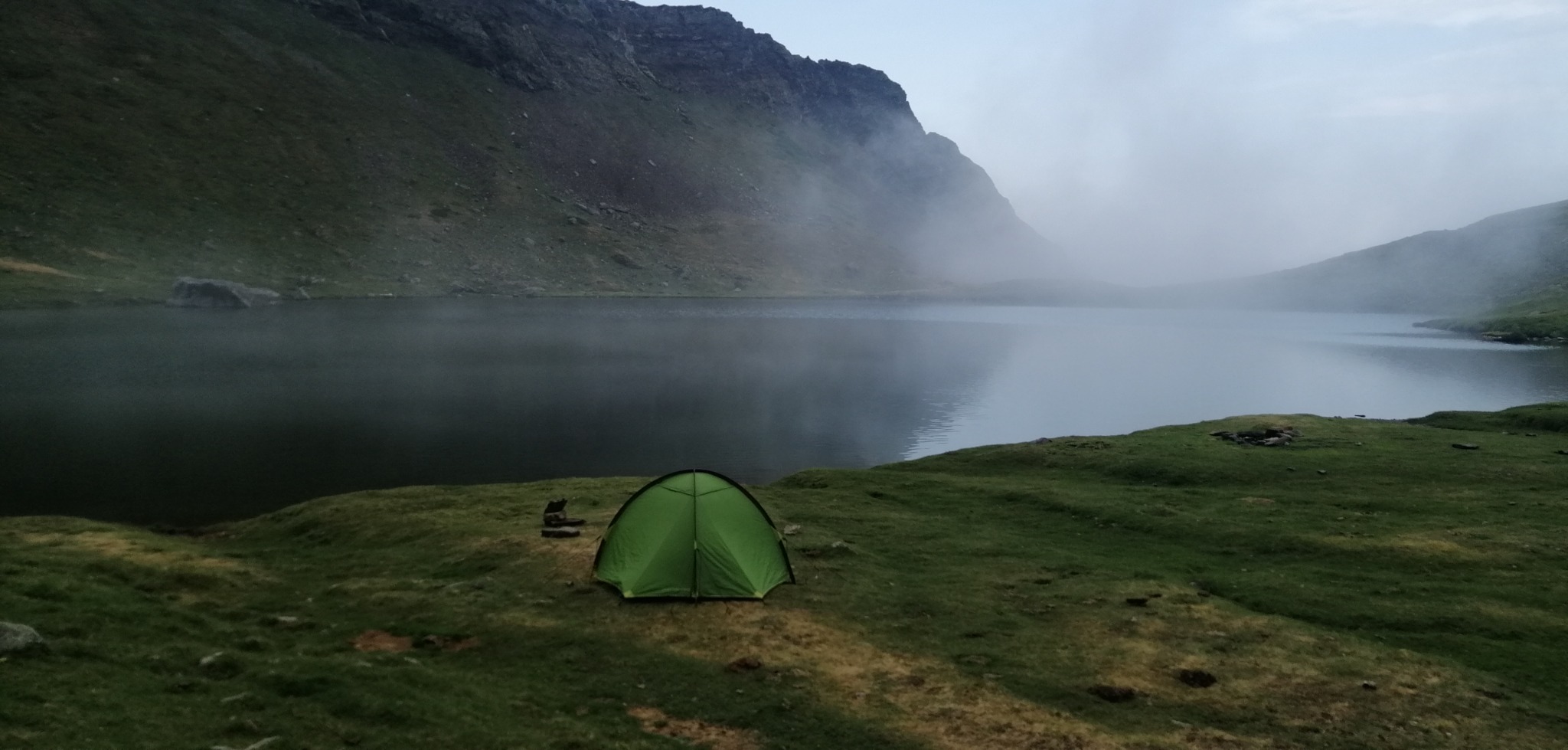 Une tente verte au bord d’un lac dans la brume, pendant le GR10 de Clément.